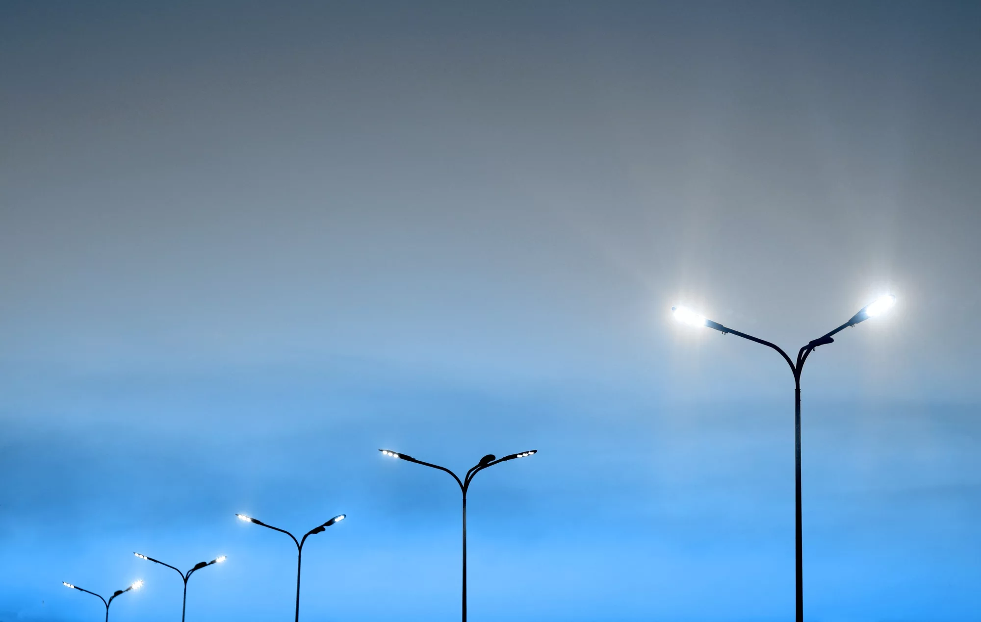 Urban landscape, illuminated street light modern lanterns and vibrant blue sky.